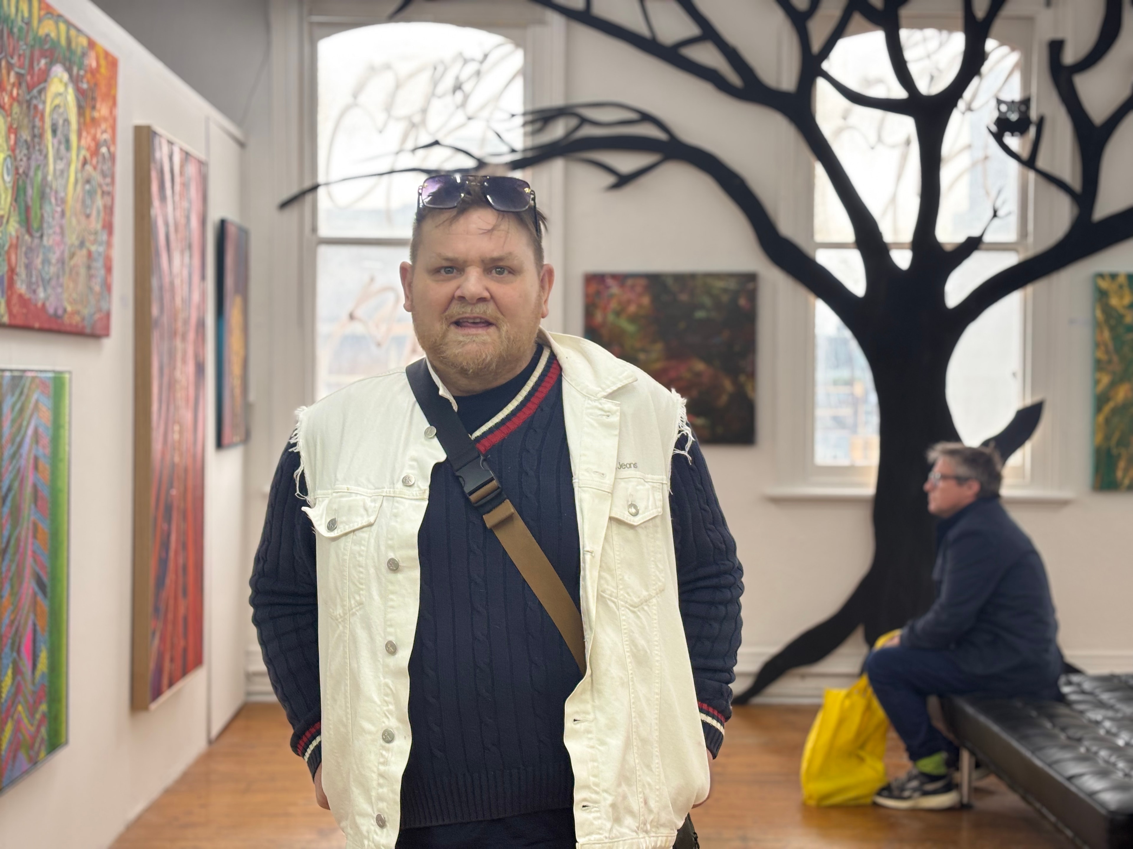 Anthony Lee standing with his work at the One Love exhibition